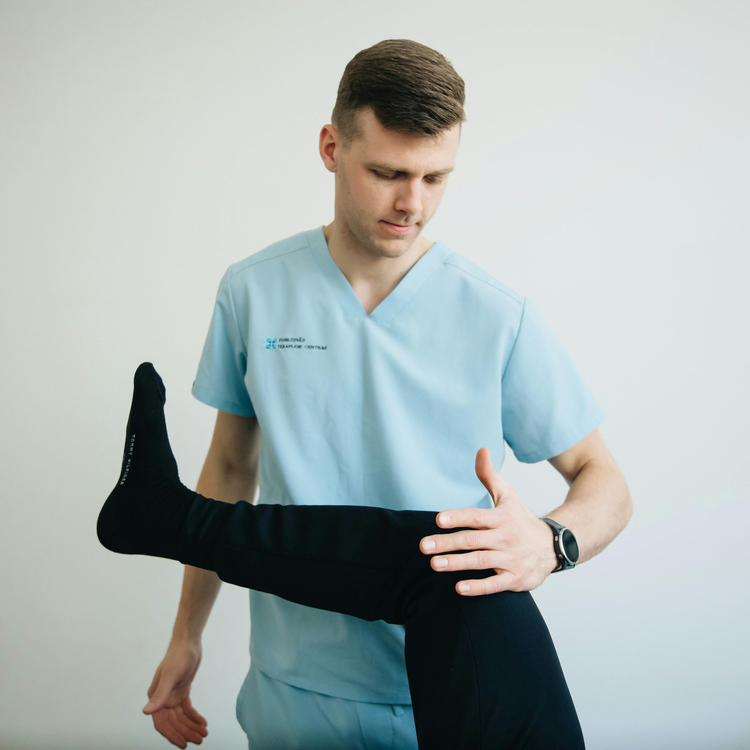 A physiotherapist assists a patient with knee pain treatment in a clinical setting.